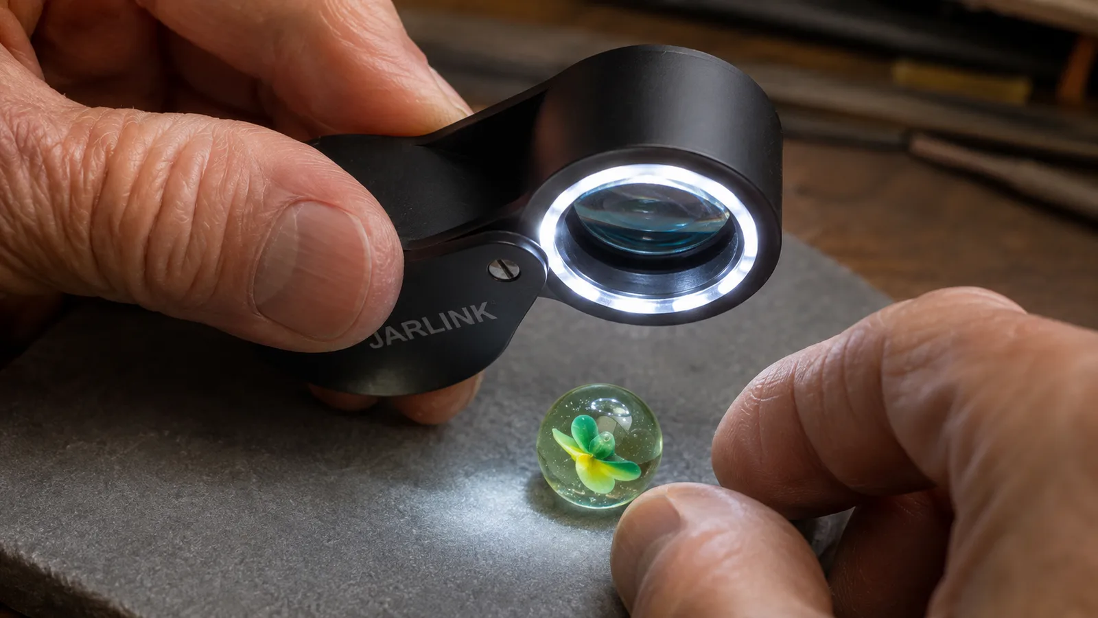 Close-up of the loupe's LED lens hovering an inch above a marbled glass piece being graded
